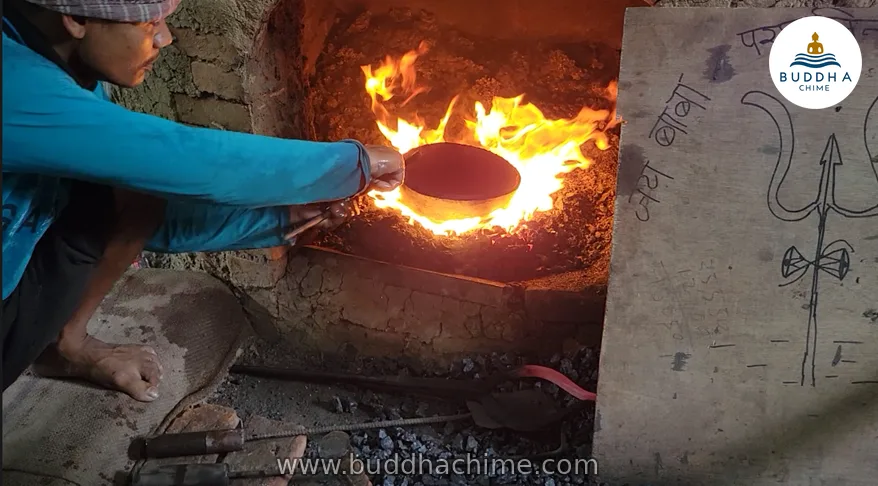 Artisan heating a singing bowl in a charcoal furnace in Kathmandu